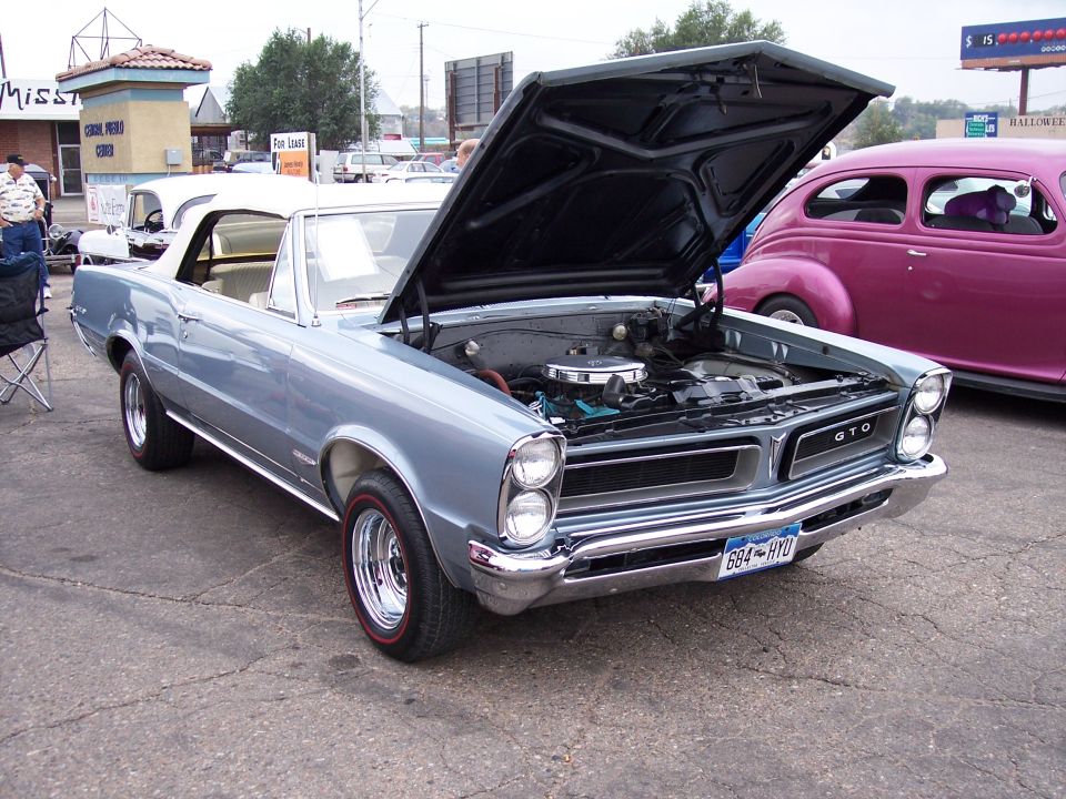 1965 Pontiac GTO convertible with hood open, parked next to a pink sedan