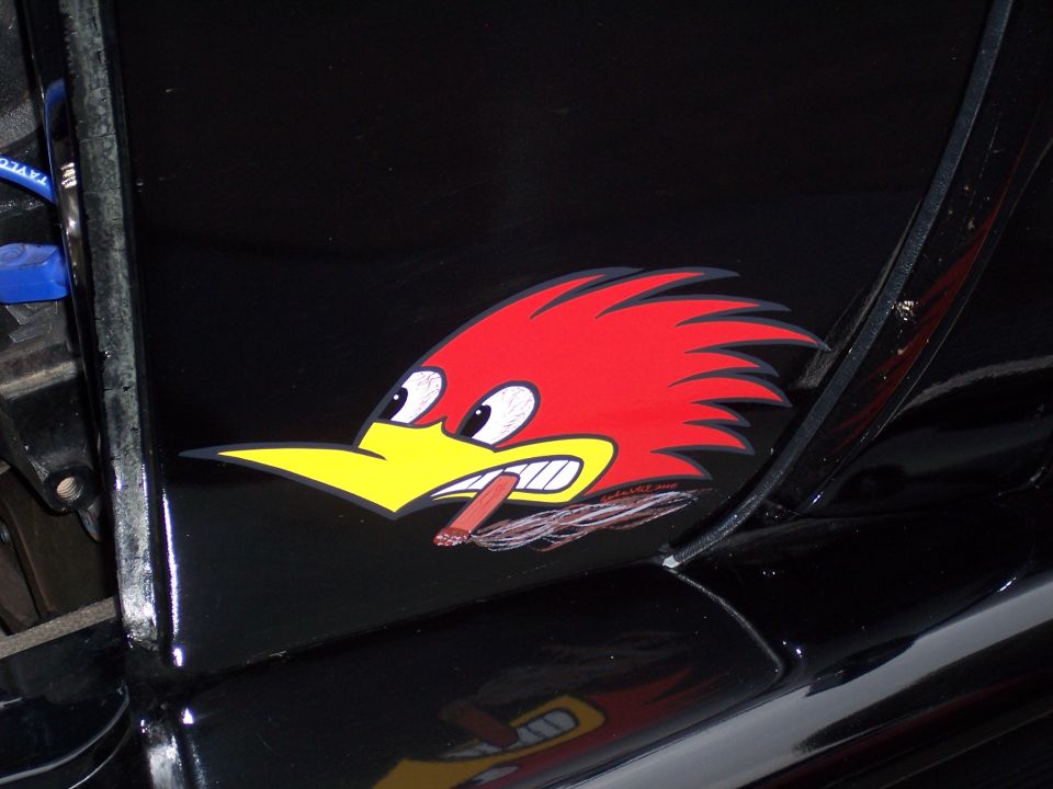 Black vehicle with a red and yellow roadrunner decal smoking a cigar