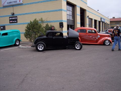 1972 Ford Ranchero - Several custom hot rods are parked outside a building with garage doors.
