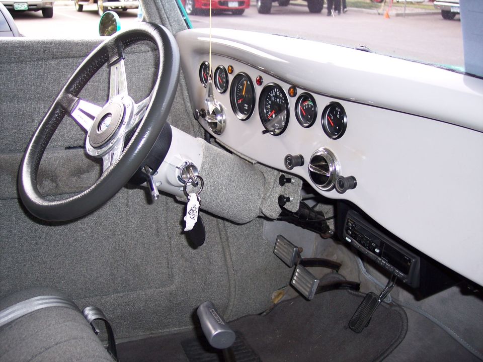 Car interior with aftermarket gauges, a custom steering wheel, and a floor shifter