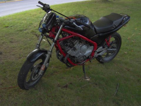 1993 Yamaha Seca II - A motorcycle with a red frame and black bodywork is parked on a grassy area next to a road.