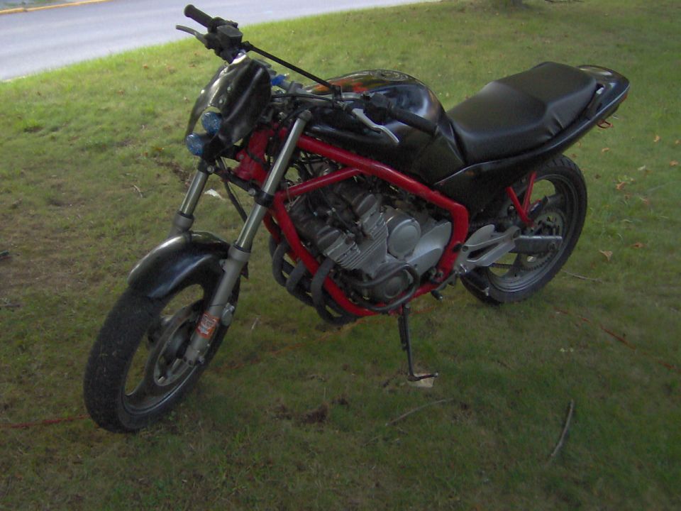 Motorcycle with red frame and black bodywork parked on grass