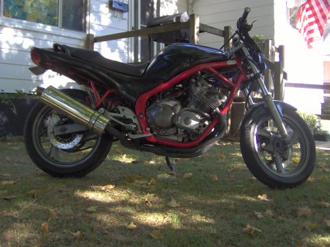 1993 Yamaha Seca II - A motorcycle with a red frame and chrome exhaust sits on a grassy lawn in front of a house.