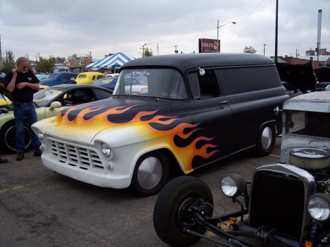 1972 Ford Ranchero - A custom panel van with flame decals is parked at an outdoor car show with other vehicles present.
