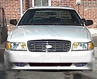 1987 Ford Crown Victoria LTD - This silver sedan is captured from a front-facing perspective, highlighting its grille and headlight design.