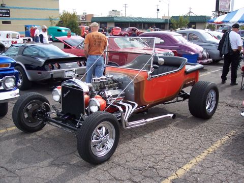 1972 Ford Ranchero - A bright orange hot rod with a powerful engine and custom exhaust system is displayed at a car show.