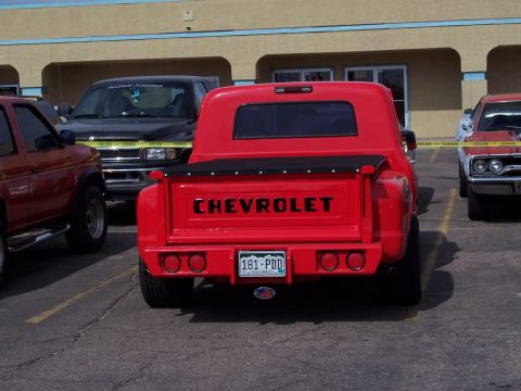 1972 Ford Ranchero - A bright red Chevrolet pickup truck is parked in a lot, showing its rear end with a black tonneau cover and a Colorado license plate.