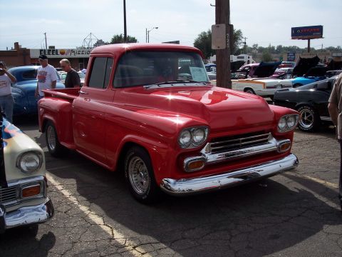 1972 Ford Ranchero - A shiny red pickup truck is parked at an outdoor event with other cars around it.
