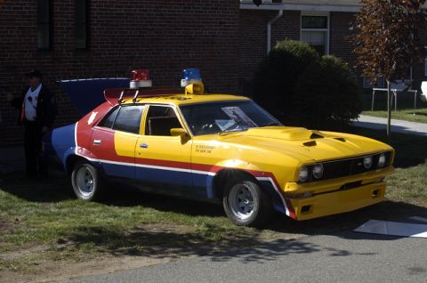 1973 Dodge 1500 - This customized sedan features a striking yellow, red, white, and blue paint scheme with emergency lights on the roof.