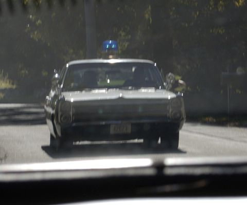 1973 Dodge 1500 - A police car, possibly a 1973 model, is seen from the front with its emergency light activated.