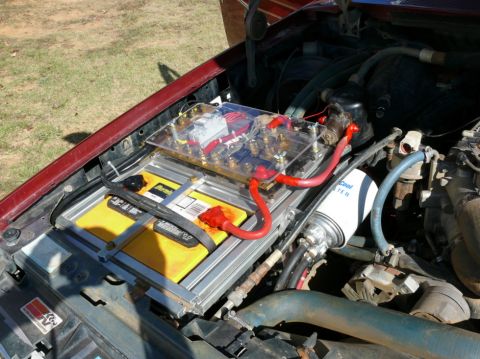 1988 Ford Bronco - Close-up of an aftermarket battery and electrical distribution system installed in a vehicle's engine compartment.