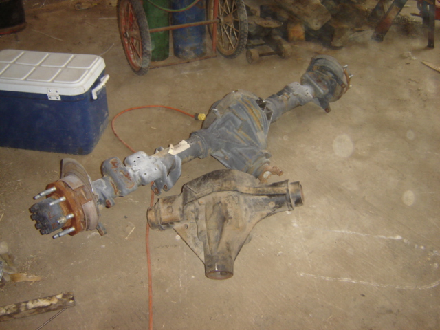 Two vehicle axles on a concrete floor, one with a brake rotor and hub assembly