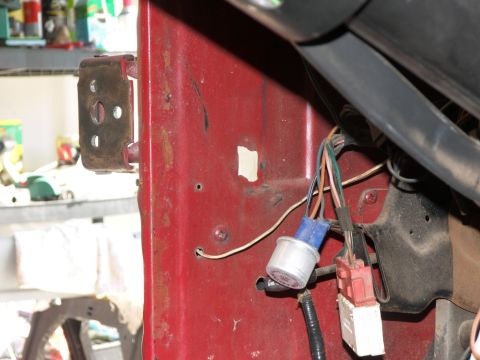 1978 Ford Bronco - Close-up view of wiring and a door latch mechanism inside a vehicle's red door jamb.
