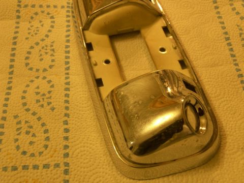 1978 Ford Bronco - A close-up view of a chrome-plated interior trim piece, likely for a vehicle, is shown resting on a textured cloth.