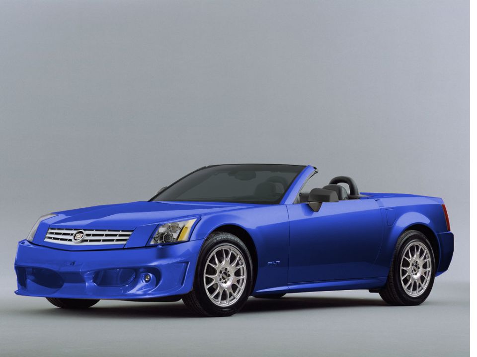 Studio photo of a bright blue Cadillac XLR roadster, top down, front three-quarter view