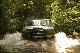 1996 Ford Bronco - An SUV navigates through a shallow body of water, kicking up spray.