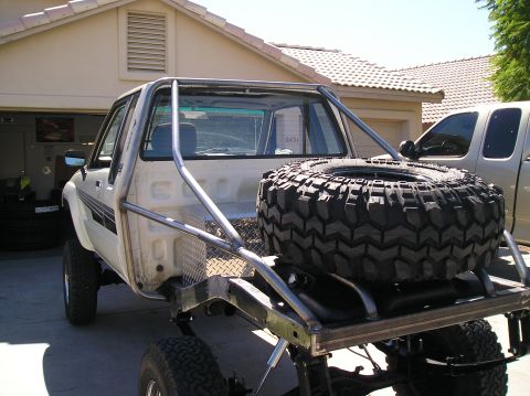 1986 Toyota Hilux - Modified 1986 Toyota Hilux pickup truck with a custom tube bed and spare tire, parked in a driveway.