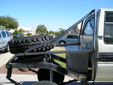 1986 Toyota Hilux - Custom tubular flatbed with stacked off-road tires and diamond-plate toolbox mounted behind a Ford EFI truck cab.