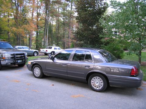 1991 Ford LTD Crown Victoria - Side view of a gray Ford Crown Victoria with other vehicles in the background.