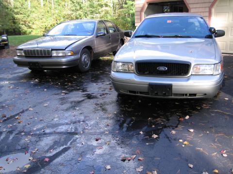 1991 Ford LTD Crown Victoria - A silver Ford Crown Victoria is parked in a driveway with another car behind it.