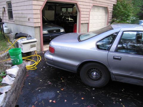 1991 Ford LTD Crown Victoria - A silver sedan is parked in front of a garage containing a blue sedan.