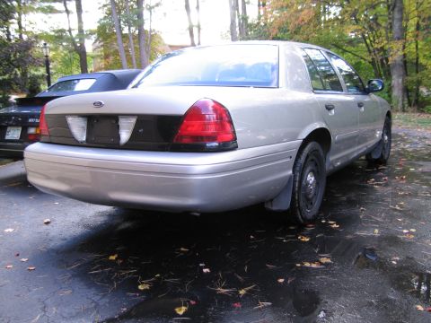 1991 Ford LTD Crown Victoria - Silver sedan with a black panel between the taillights, parked outdoors on a wet driveway.