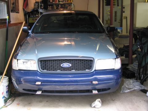 1991 Ford LTD Crown Victoria - A Ford Crown Victoria is parked inside a garage, showing its front grille and headlights.