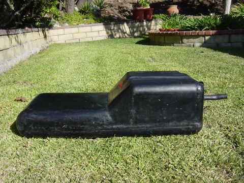 1983 Ferrari Enzo - This black fuel tank is shown resting on a grassy lawn.