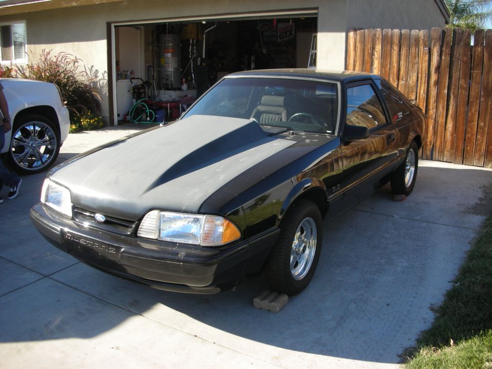 Black Ford Mustang fox-body with two-tone hood in a driveway