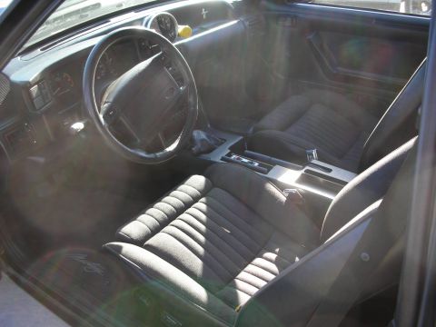 1998 Ford Crown Victoria - The interior of a car shows ribbed cloth seats and a dashboard with a steering wheel.