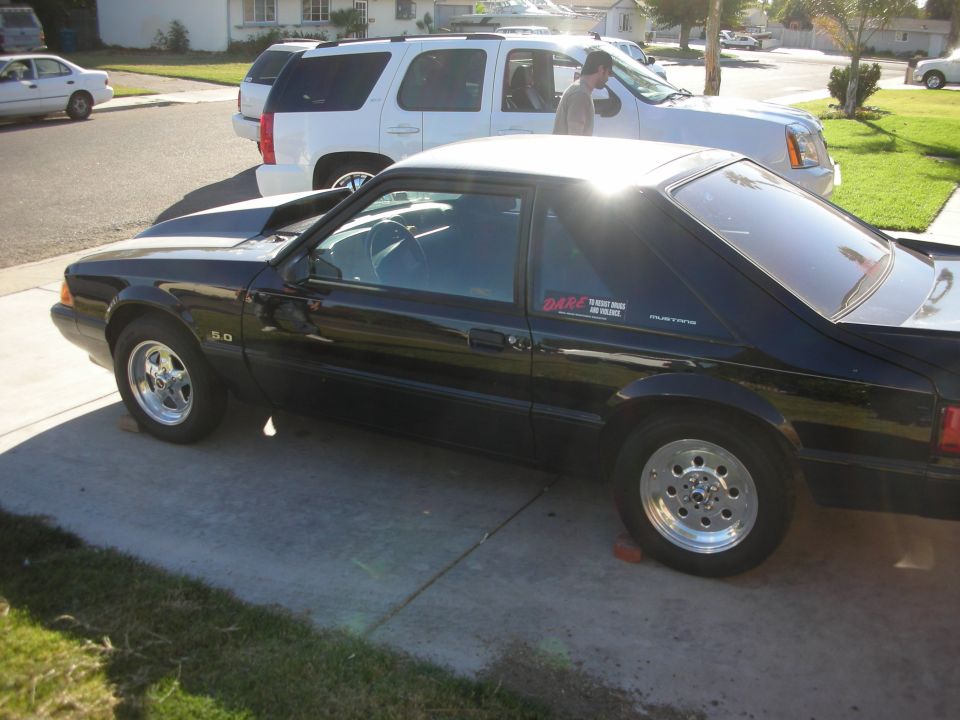 Side view of a black Fox-body Mustang hatchback with 5.0 badge