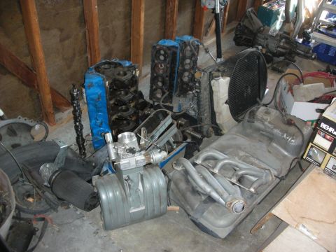 1998 Ford Crown Victoria - Various engine components are stored together in a cluttered garage space.