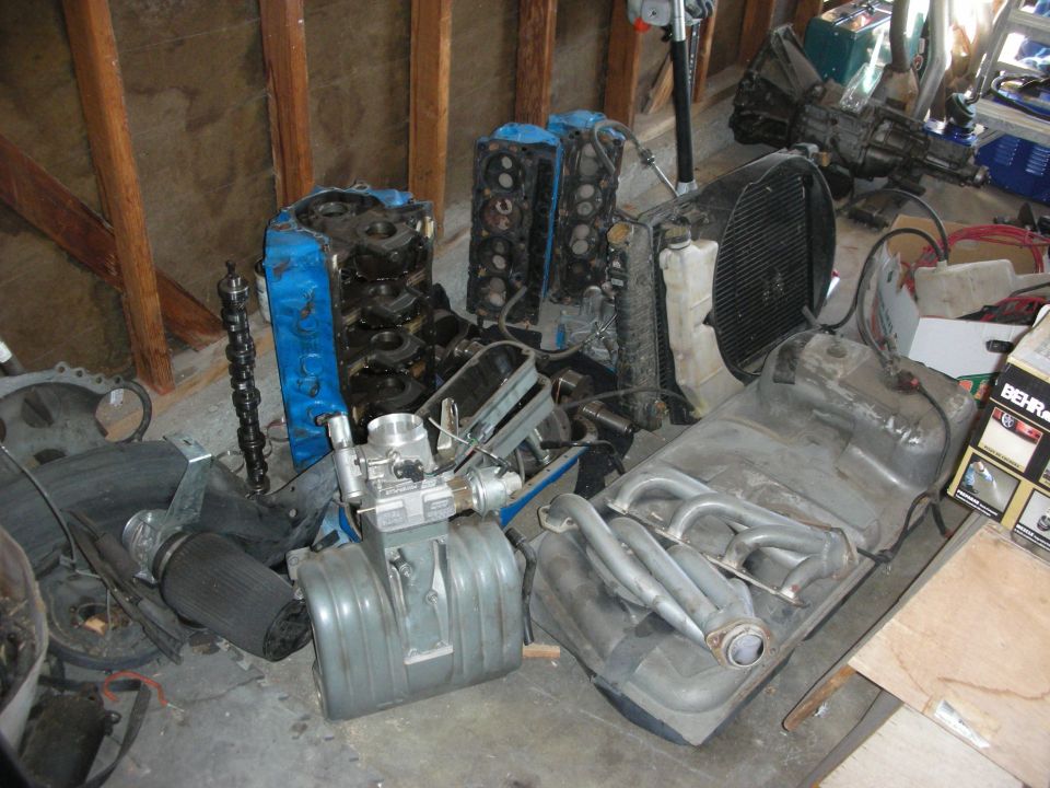 Disassembled V8 engine parts and cylinder heads on a garage floor