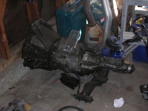 1998 Ford Crown Victoria - Manual transmission and exhaust parts are stored indoors on a concrete floor.
