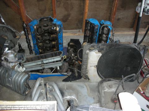 1998 Ford Crown Victoria - Various engine components are disassembled and stored, including a blue engine block and a large radiator fan.
