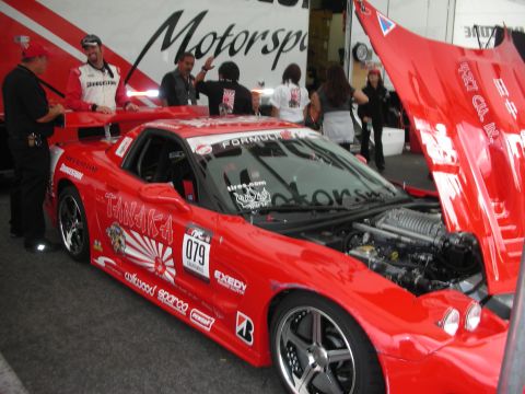 1998 Ford Crown Victoria - A red race car is parked with its hood open, revealing the engine and supercharger.