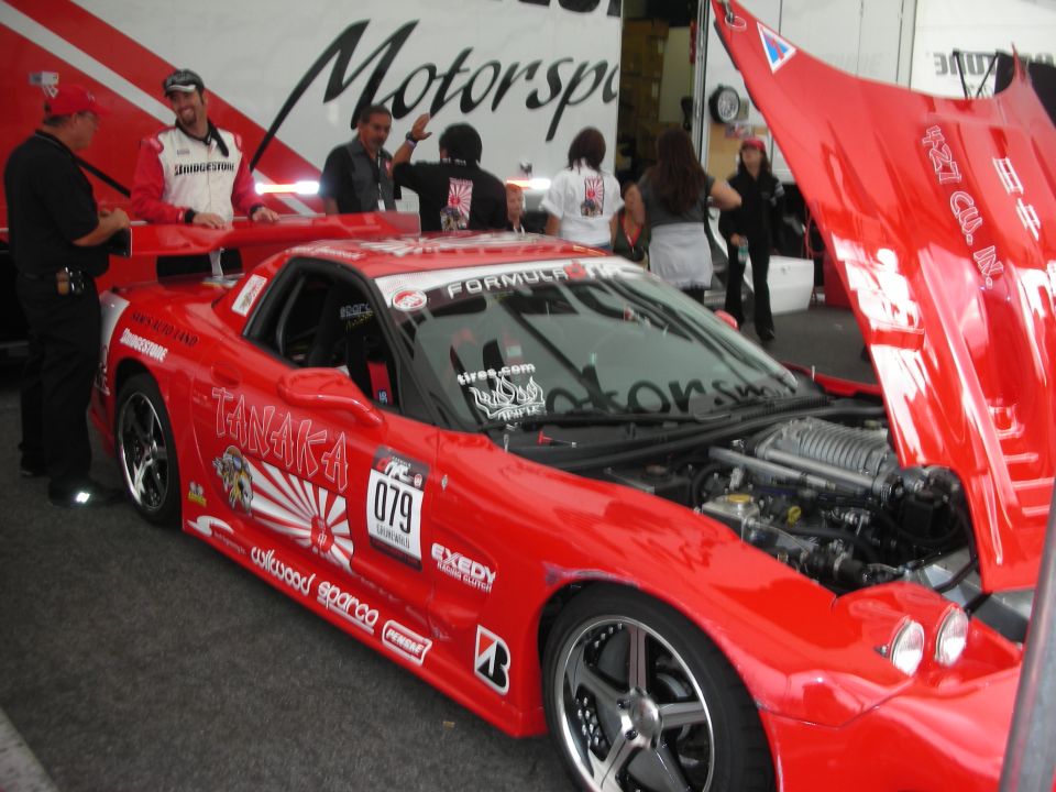 Red Tanaka race car with rising-sun and Formula D livery in paddock
