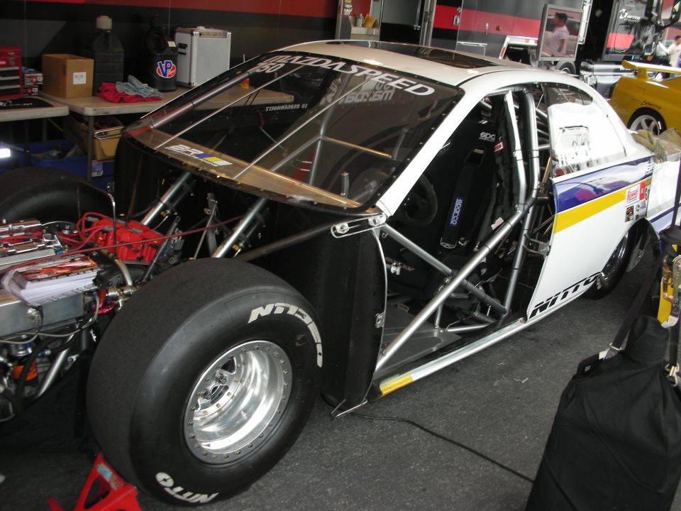 Tube-chassis drag race car body with Nitto slicks in garage