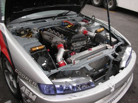 1998 Ford Crown Victoria - Customized engine bay of a silver car, modified for racing with visible aftermarket parts.