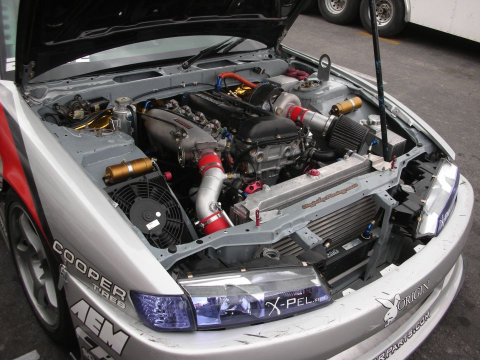 Engine bay of silver Nissan drift car with tucked turbo setup