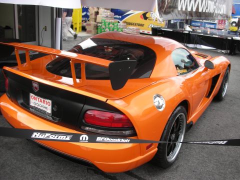 1998 Ford Crown Victoria - Orange Dodge Viper with a prominent rear spoiler and custom wheels, seen at an event.