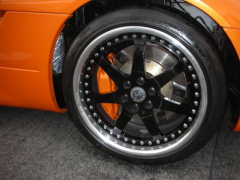 1998 Ford Crown Victoria - Close-up of an orange car's wheel, custom black spokes and vibrant orange brake calipers.
