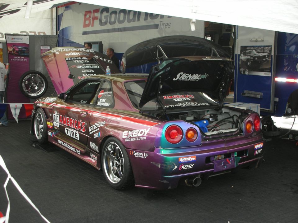 Purple-green chrome Nissan Skyline with hood and hatch open in tent