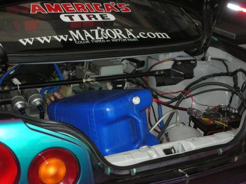1998 Ford Crown Victoria - Custom car trunk setup with a fuel cell and battery, plus sponsor stickers on the rear window.