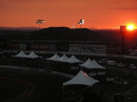1998 Ford Crown Victoria - A wide view of Irwindale Speedway at sunset, with tents and several vehicles visible on the track grounds.