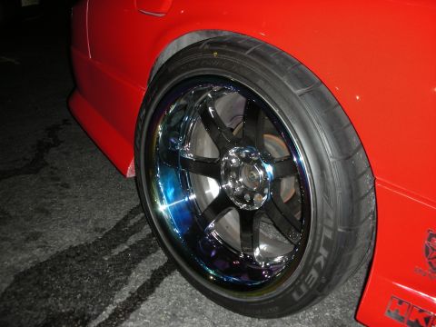 1998 Ford Crown Victoria - Close-up of a red car's rear wheel custom chrome rims and performance tires.