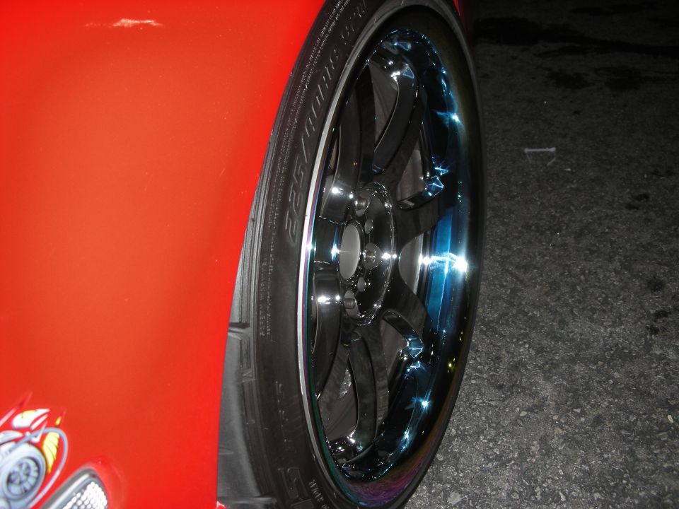 Black multi-spoke wheel with blue-tinted chrome lip on red car