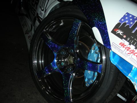 1998 Ford Crown Victoria - A highly customized car wheel and fender assembly with glitter paint and racing decals is visible.