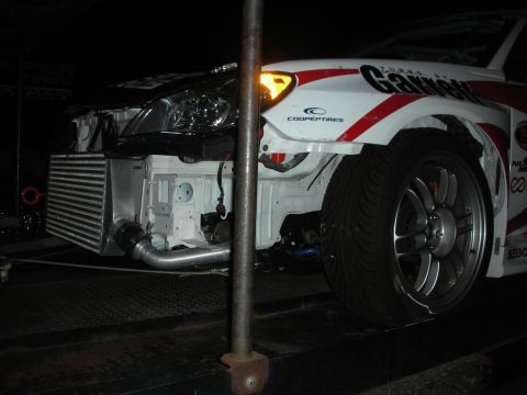 1998 Ford Crown Victoria - A white racing car with prominent sponsor decals is shown with its front end disassembled, revealing the intercooler and engine components.