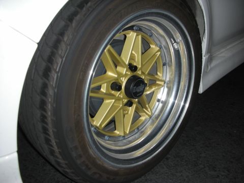 1998 Ford Crown Victoria - Close-up of a white car's front wheel gold aftermarket rims and a black center cap.